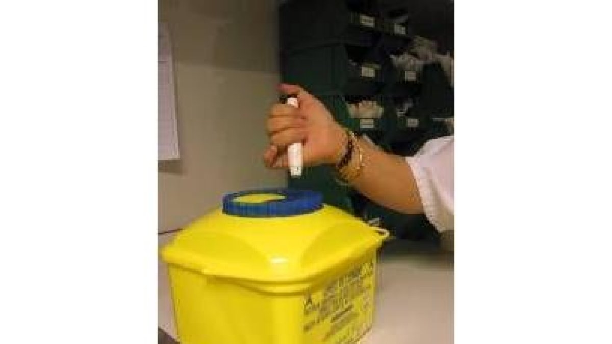 Una enfermera deposita una aguja en un contenedor especial