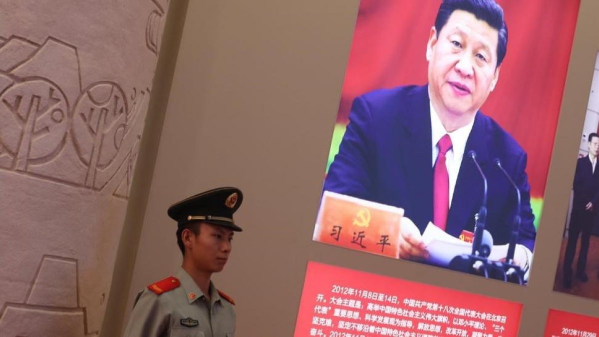 Un agente de policía permanece junto a una foto del presidente Xi Jinping, exhibida en una exposición sobre los logros de China en los últimos cinco años, en Pekín.