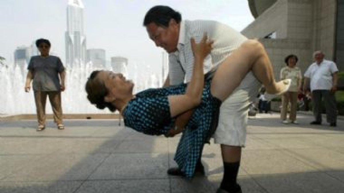 Una pareja de chinos  bailan en una plaza de la ciudad de Shanghai