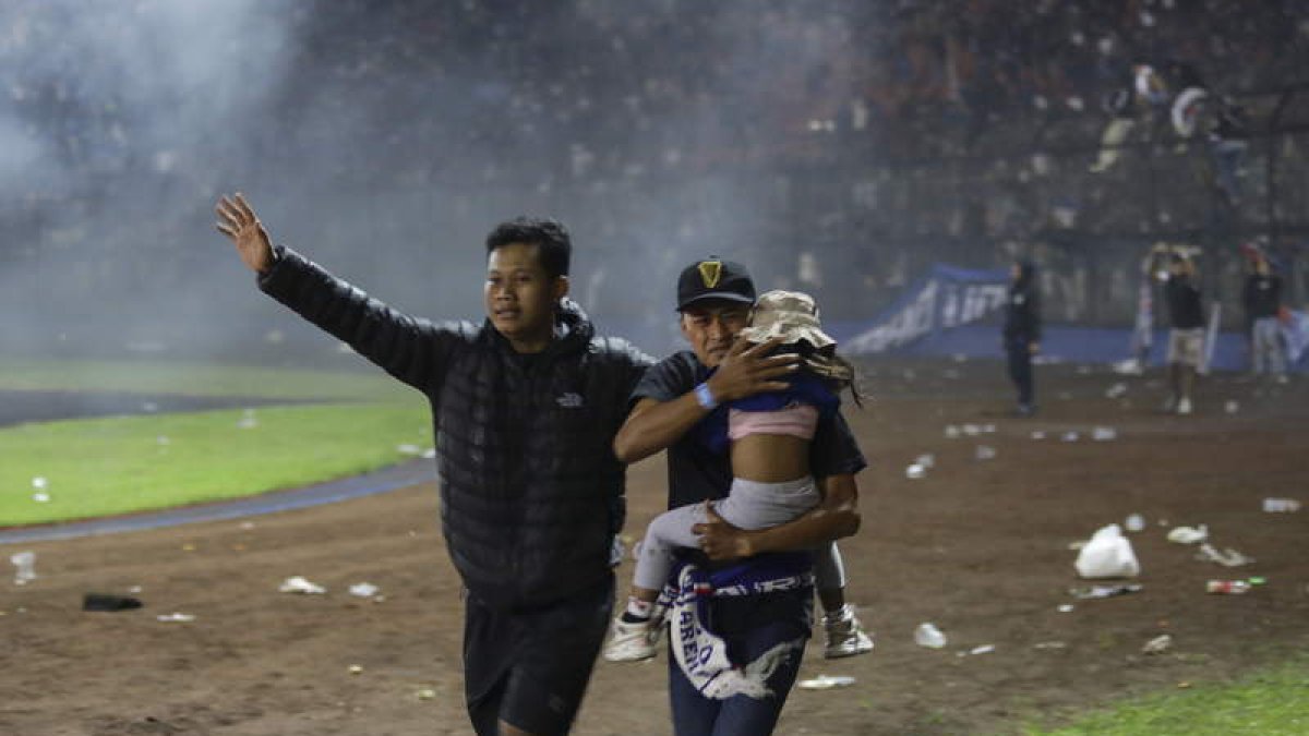 Un padre trata de poner a salvo a su hijo tras desatarse la estampida en el campo del Arema. H. PRABOWO