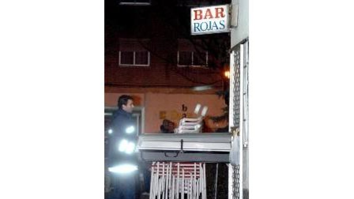 Un policía saca el cuerpo de una de las víctimas del crimen en el bar Rojas