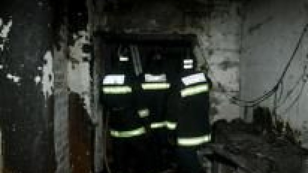 Tres bomberos comprueban el estado de la casa incendiada en la calle Cornatel