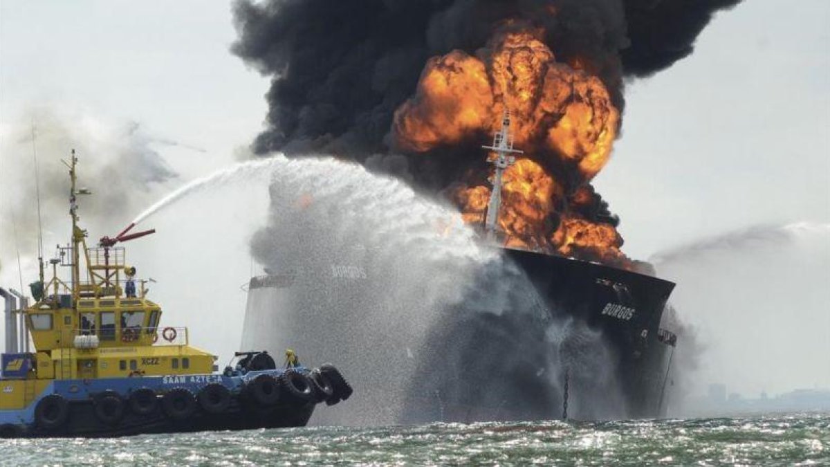 Una embarcación intenta sofocar las llamas del buque cisterna.