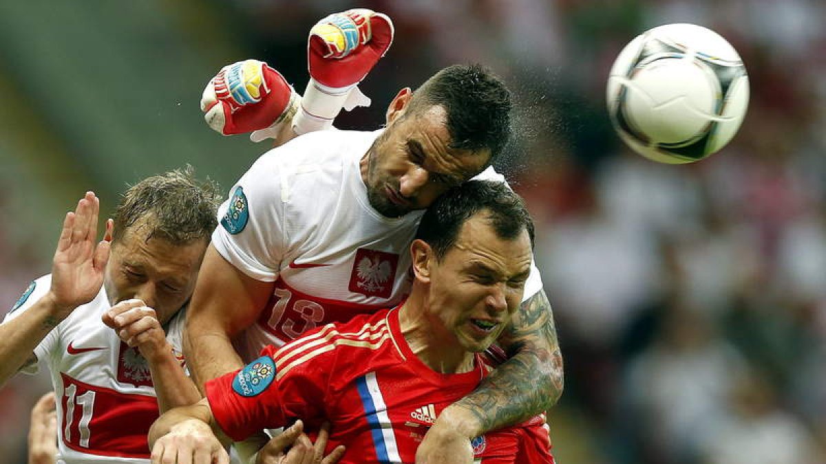 Los jugadores de Polonia Murawski y Wasilewski buscan el balón ante Ignashevich, de Rusia.