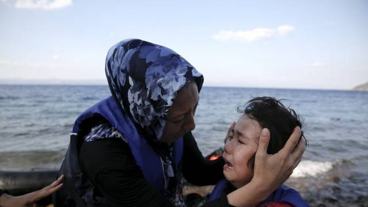 Una mujer afgana tranquiliza a su hija, que llora de miedo después de la travesía por mar entre Turquía y Grecia.