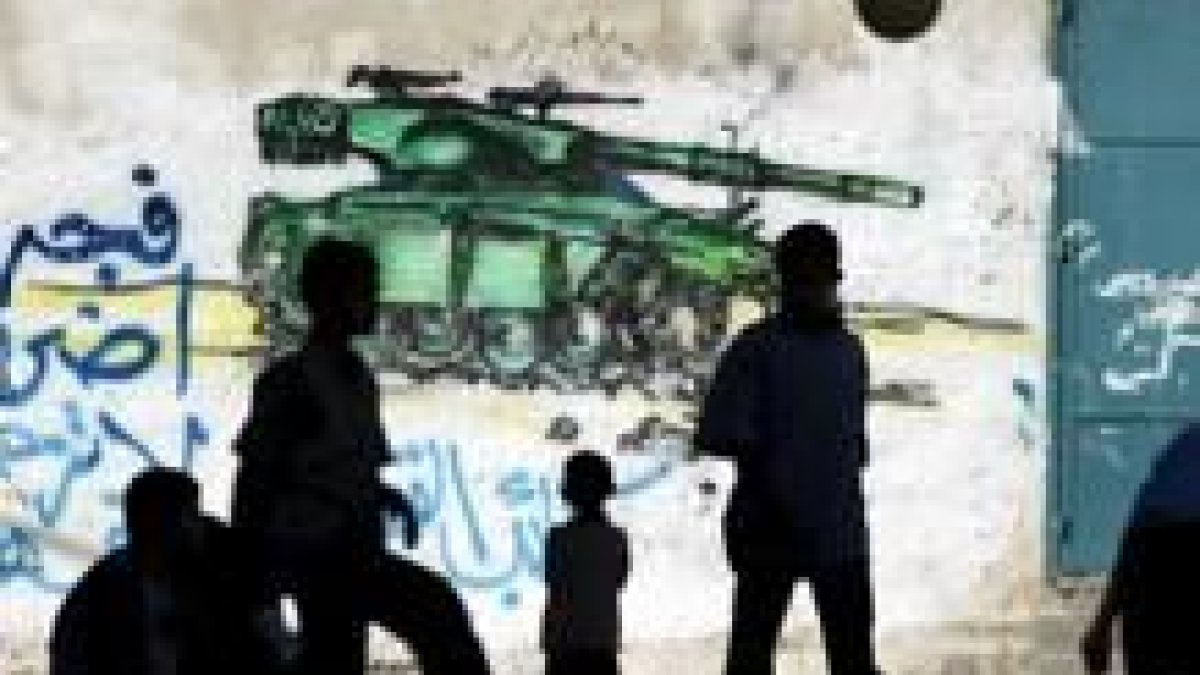 Niños palestinos juegan ante una pintada alusiva a la guerra contra Israel