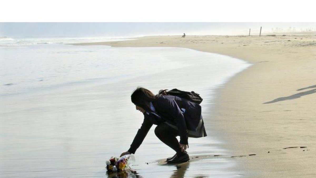 Mai Otomo, estudiante de 17 años, deja un ramo de flores en el mar en recuerdo de su padre y dos compañeros fallecidos.
