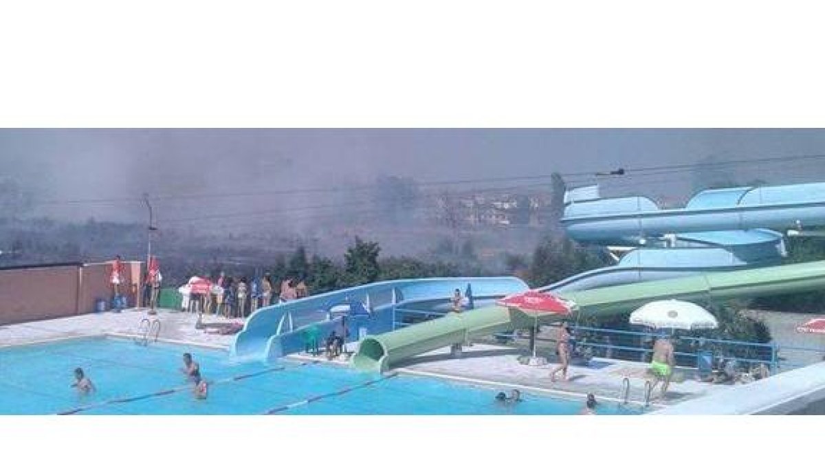 Usuarios de la piscina de Toboganes de Trobajo contemplan el incendio mientras otros siguen bañándose