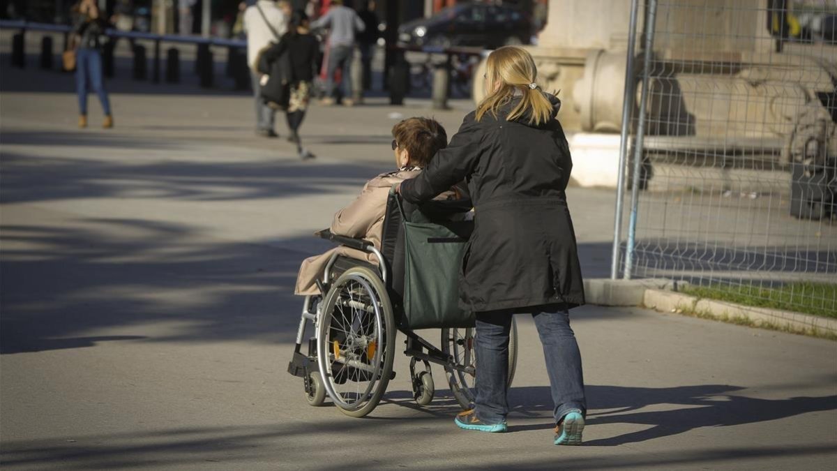 Una mujer acompaña a otra en silla de ruedas en Barcelona.