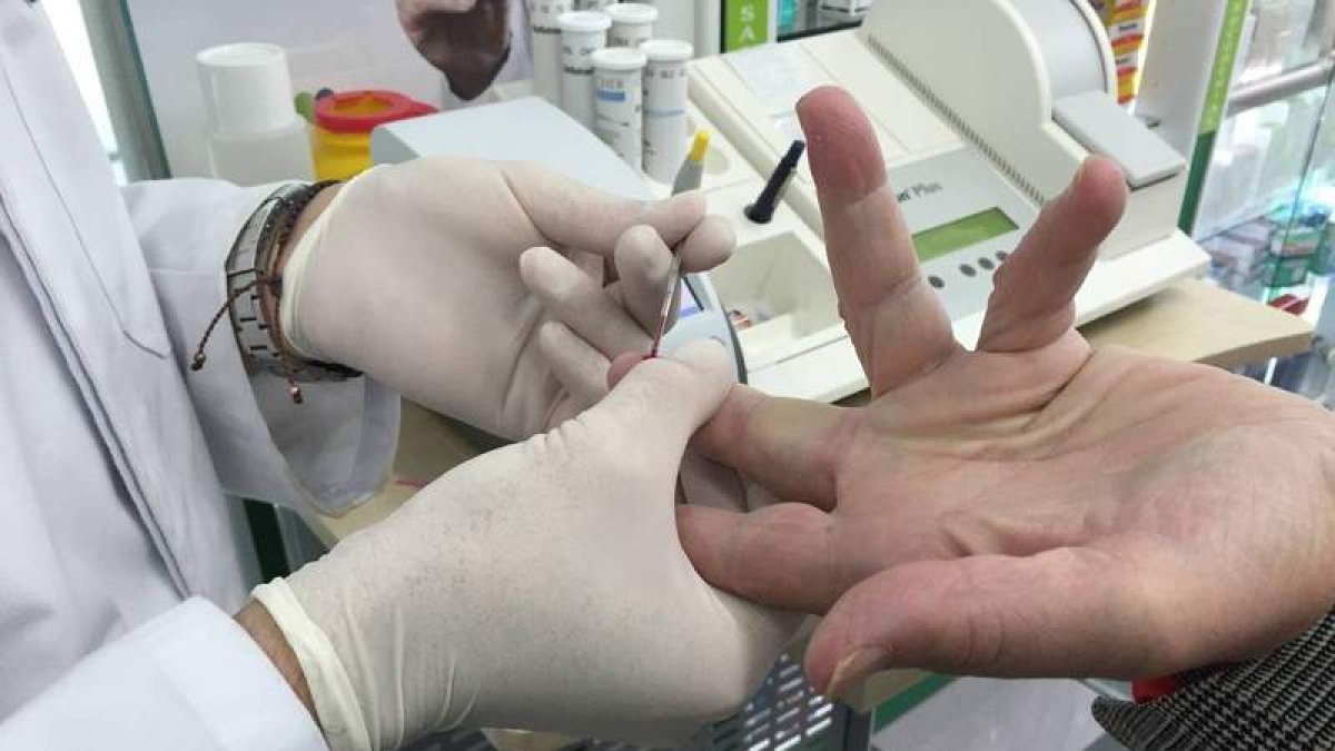 El farmacéutico realiza una prueba para la detección rápida del virus del sida a un usuario.