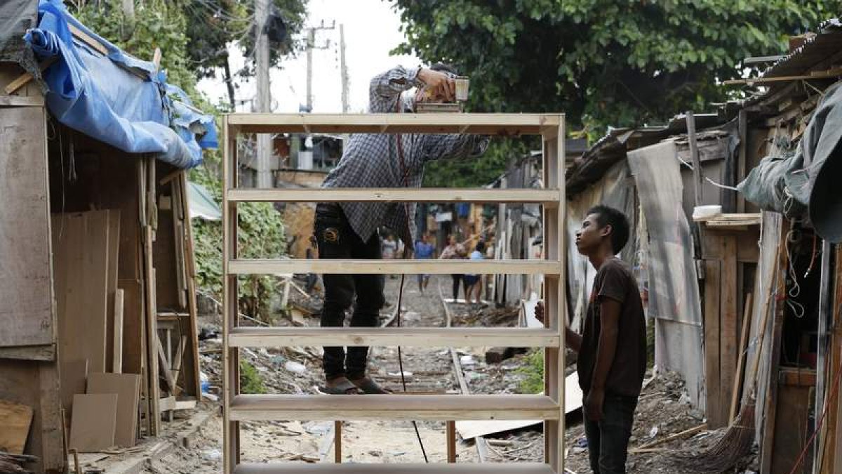 Dos artesanos fabrican una estantería con palés de madera en el barrio pobre de Khlong Toey, en Bangkok. BÁRBARA WALTON