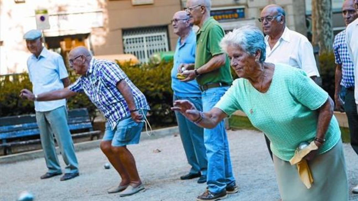Un grupo de pensionistas juega a petanca en un parque.
