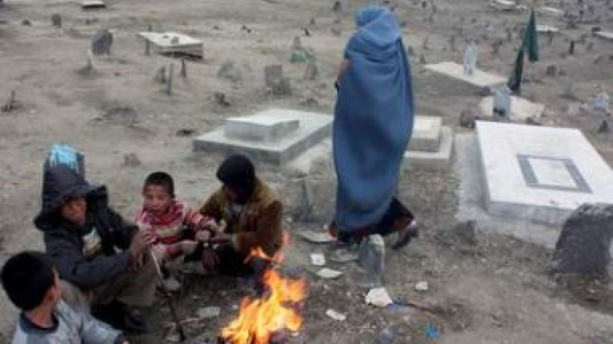 Varios niños combaten el frío alrededor de una hoguera en un cementerio de Kabul.