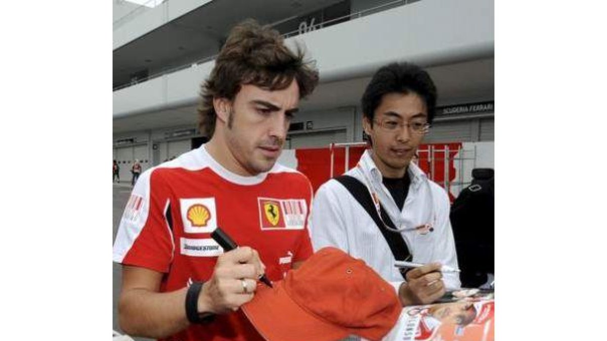 Fernando Alonso firma autógrafos en Sepang.