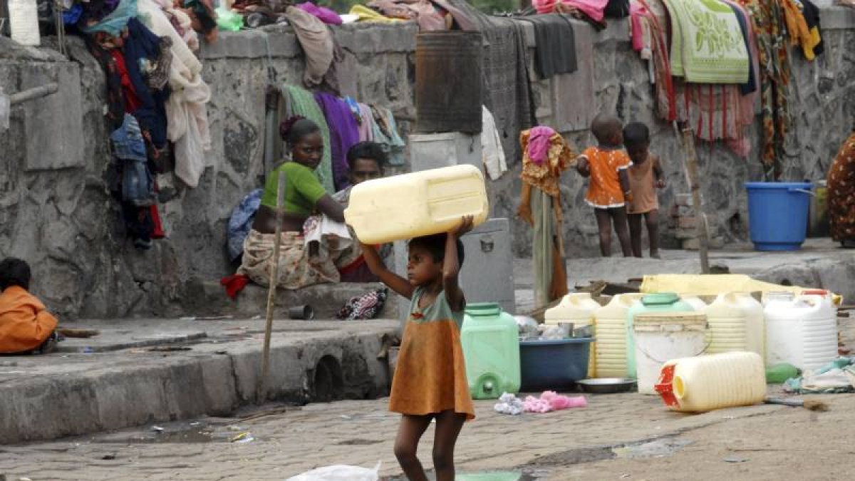 Una niña huérfana carga con un bidón para el agua en Bombai (India).