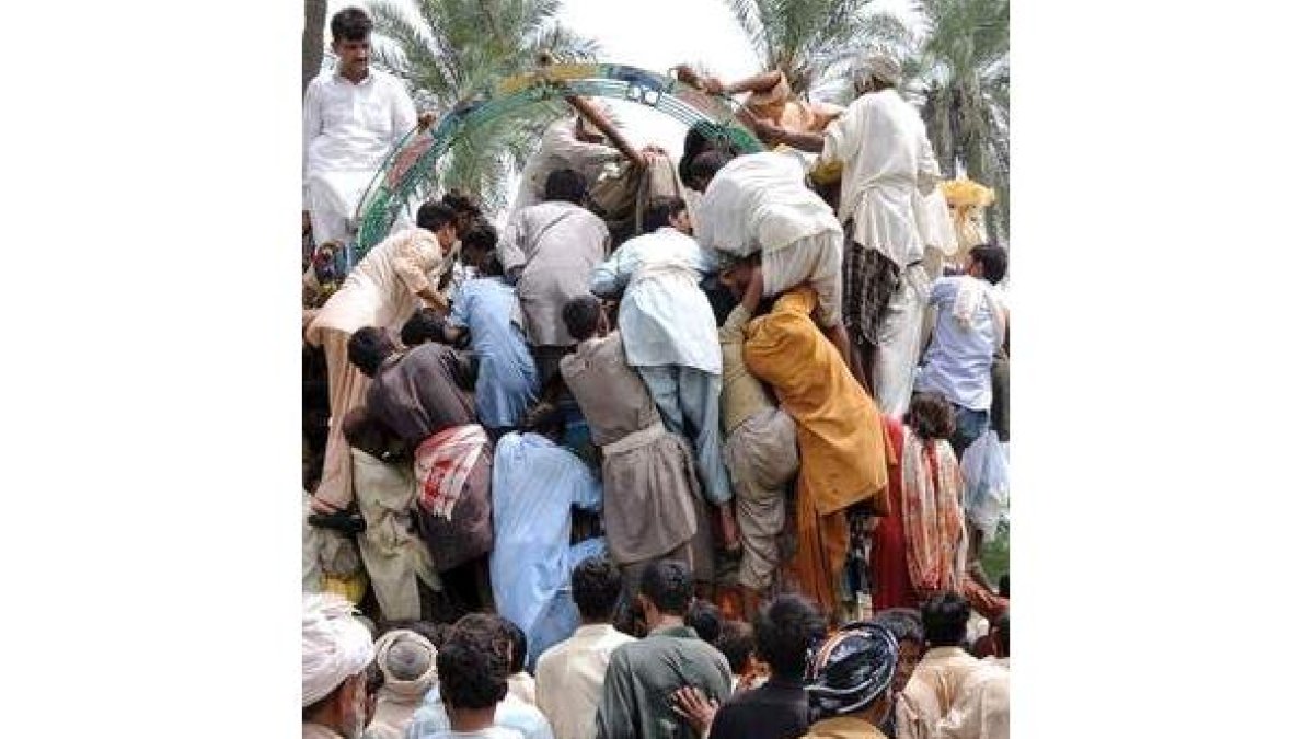 Varios desplazados saquean un camión de distribución de alimentos en Basera, Pakistán.