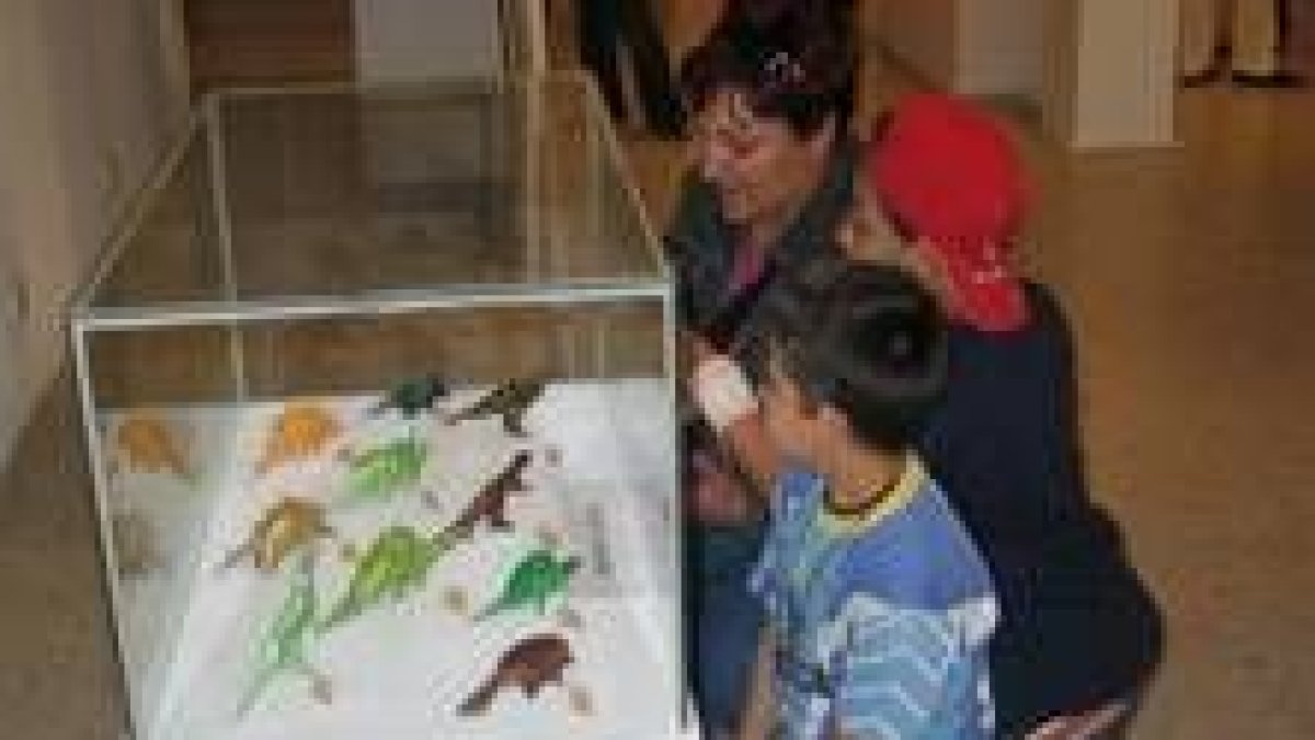 Unos niños contemplan sorprendidos algunos de los dinosaurios hechos sólo con papel