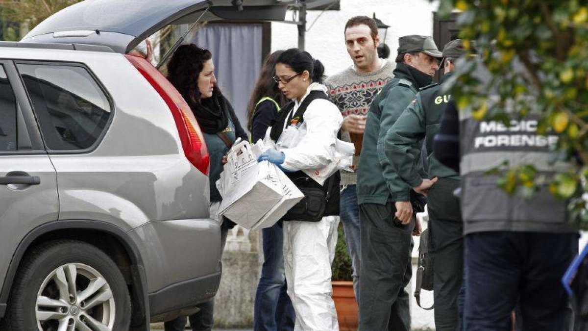 Agentes judiciales y de la Guardia Civil salen de una de las viviendas, en el municipio lucense de Cervo, donde encontraron dos cadáveres.