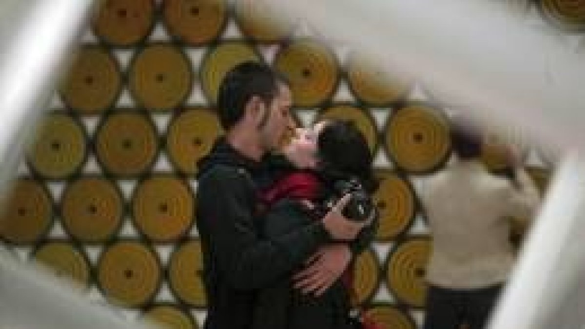 Dos artistas de abrazan ante una de las obras que pueden verse en la Bienal de Venecia