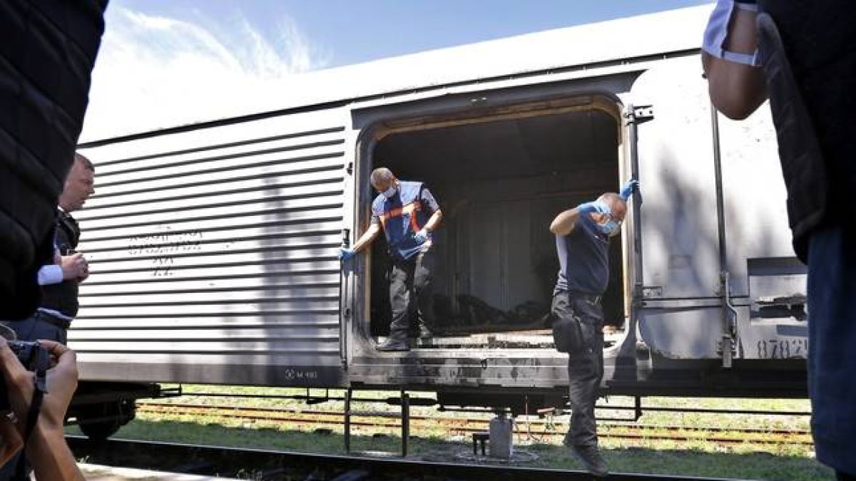 Expertos forenses holandeses saltan de un vagón refrigerado tras revisar alguno de los cadáveres de las víctimas del vuelo MH17 en una estación de tren de Torez, a unos 90 kilómetros al este de Donetsk (Ucrania) hoy, lunes 21 de julio de 2014.