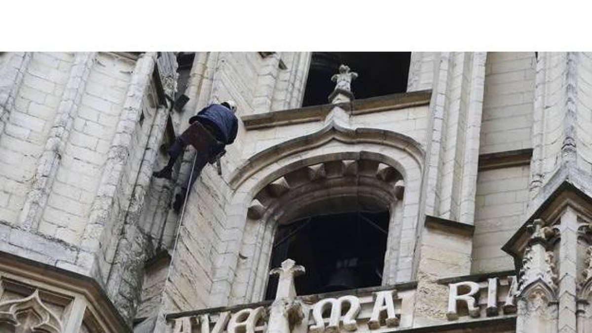 Un técnico de una empresa de trabajos verticales realizando fotos con el móvil de la Torre Sur de la Catedral de León