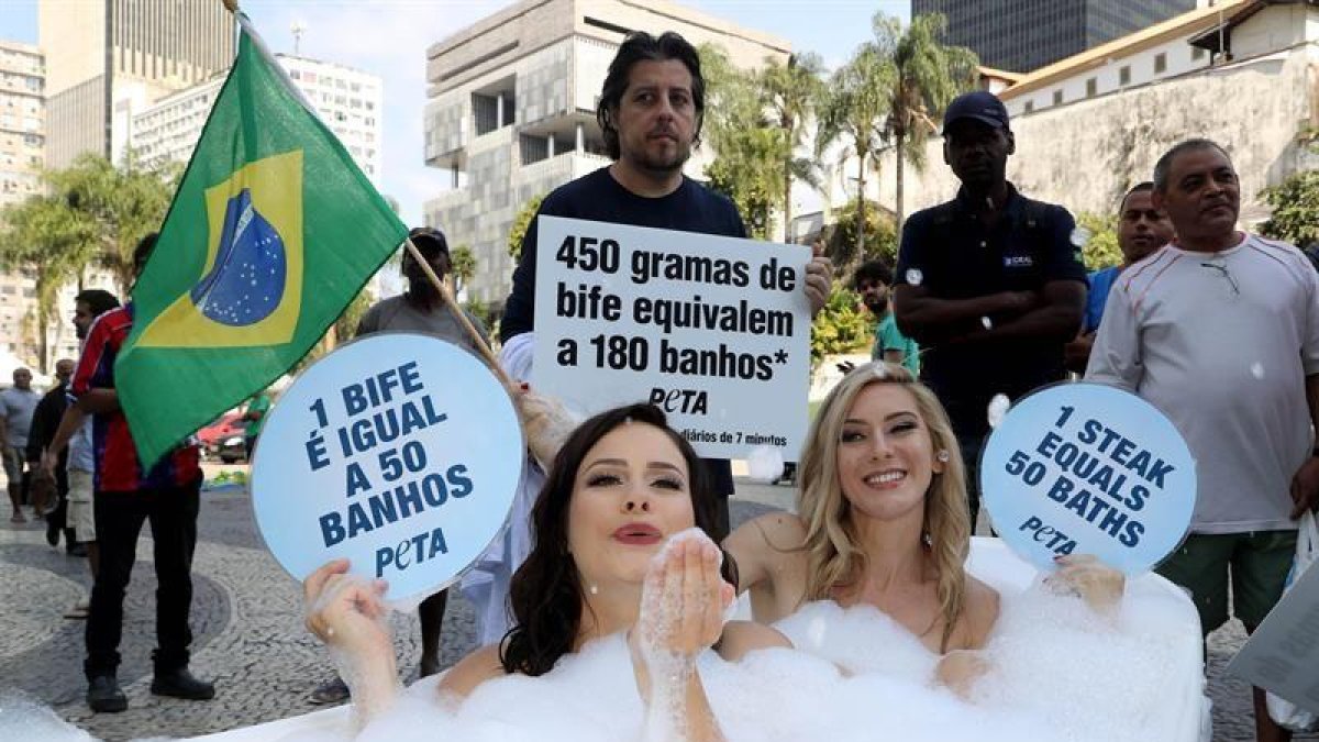 Dos activistas de la organización Personas a favor del Trato Ético a los Animales (PETA, en inglés) se bañan en una tina en el centro de Río de Janeiro hoy para denunciar que el consumo de carne supone el despilfarro de grandes cantidades de agua.