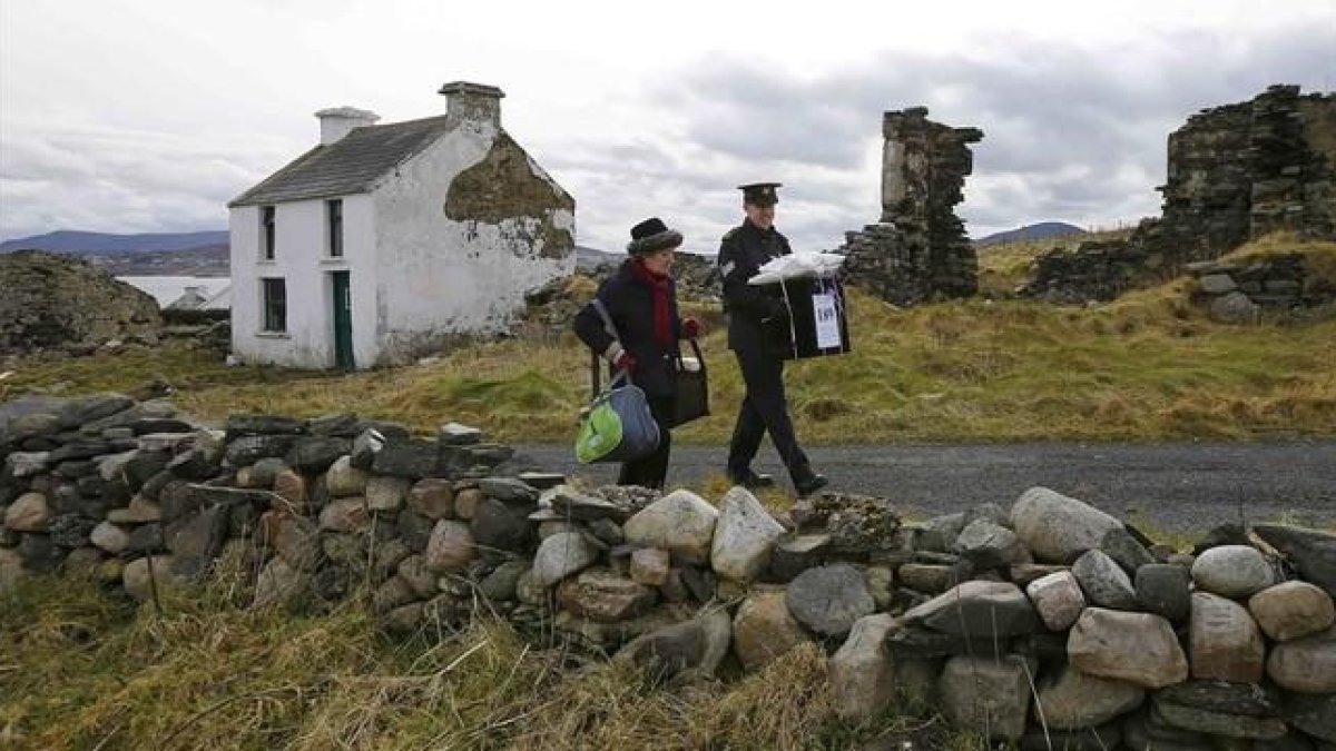 Dos oficiales se llevan la urna de la isla irlandesa de Inishbofin.