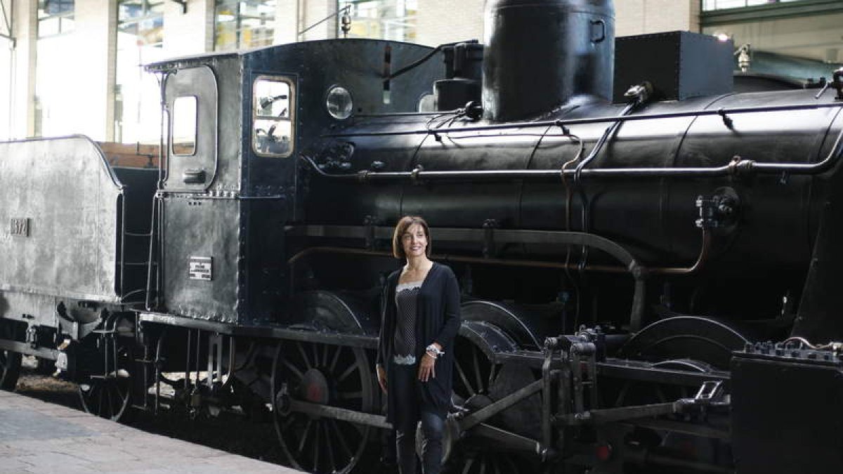 La leonesa Beatriz Fernández, que vive en Gijón hace 24 años, posa junto a uno de los trenes antiguos del Museo del Ferrocarril de la ciudad asturiana.