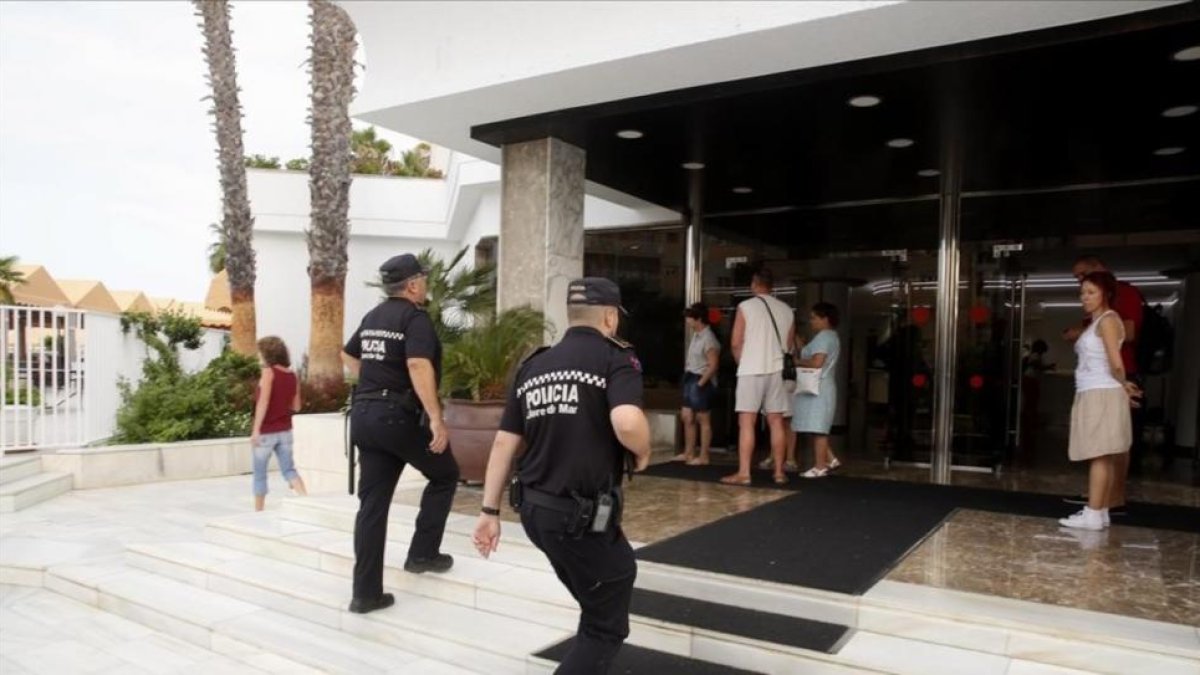 Dos agentes de la Policía Local de Lloret entran en el hotel Marina Sand, en la mañana de este viernes, para verificar que se está llevando a cabo el desalojo del establecimiento.