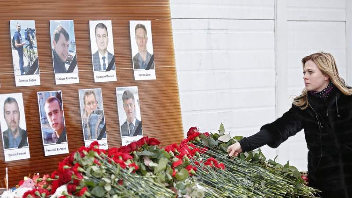 Una mujer deja flores ante los retratos de los periodistas muertos en el accidente. SERGEI ILNITSKY
