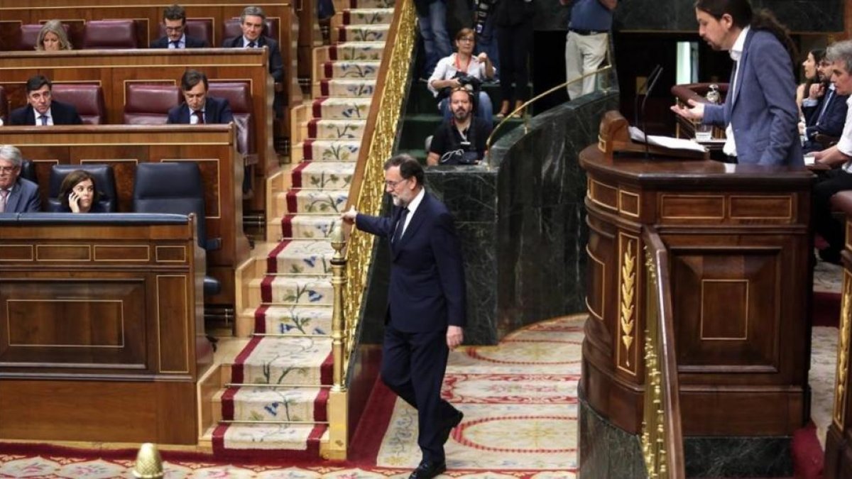 Mariano Rajoy vuelve a su escaño durante la intervención de Pablo Iglesias en la moción de censura.
