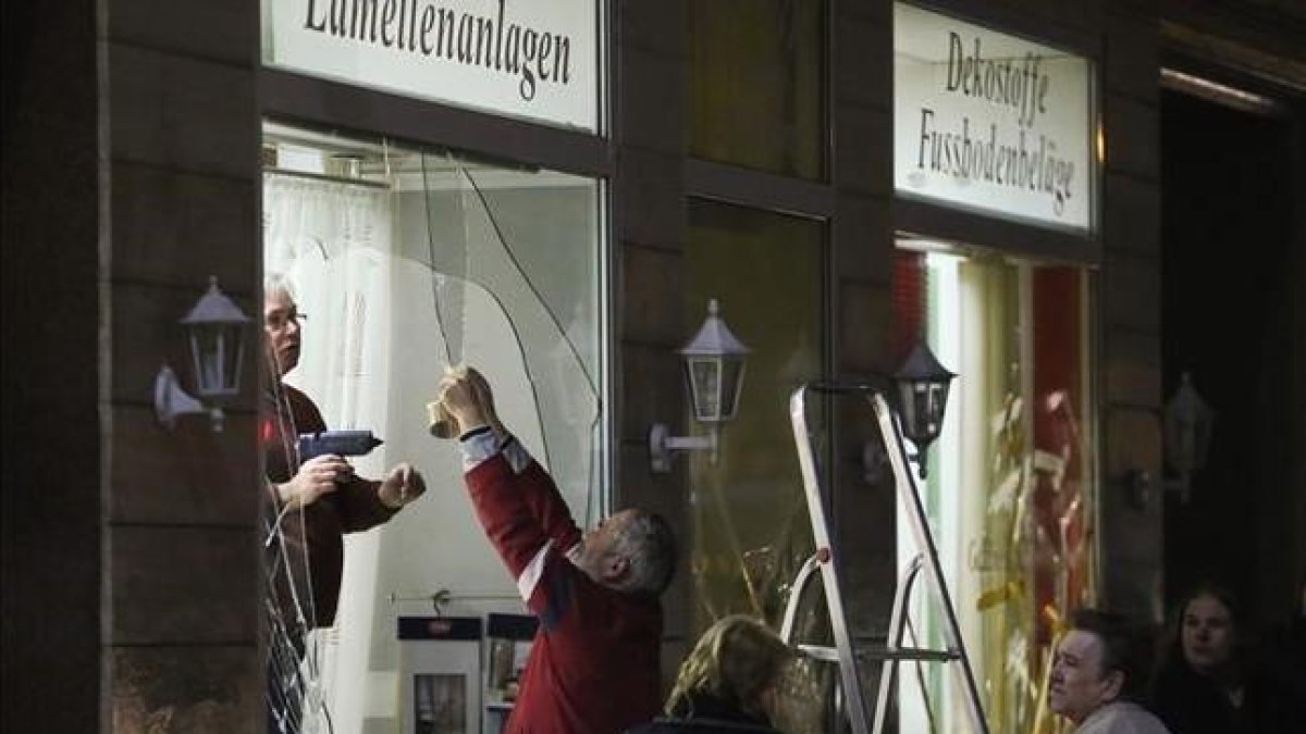Unos hombres reparan los escaparates de una tienda rotos por los manifestantes ultraderechistas en Leipzig.