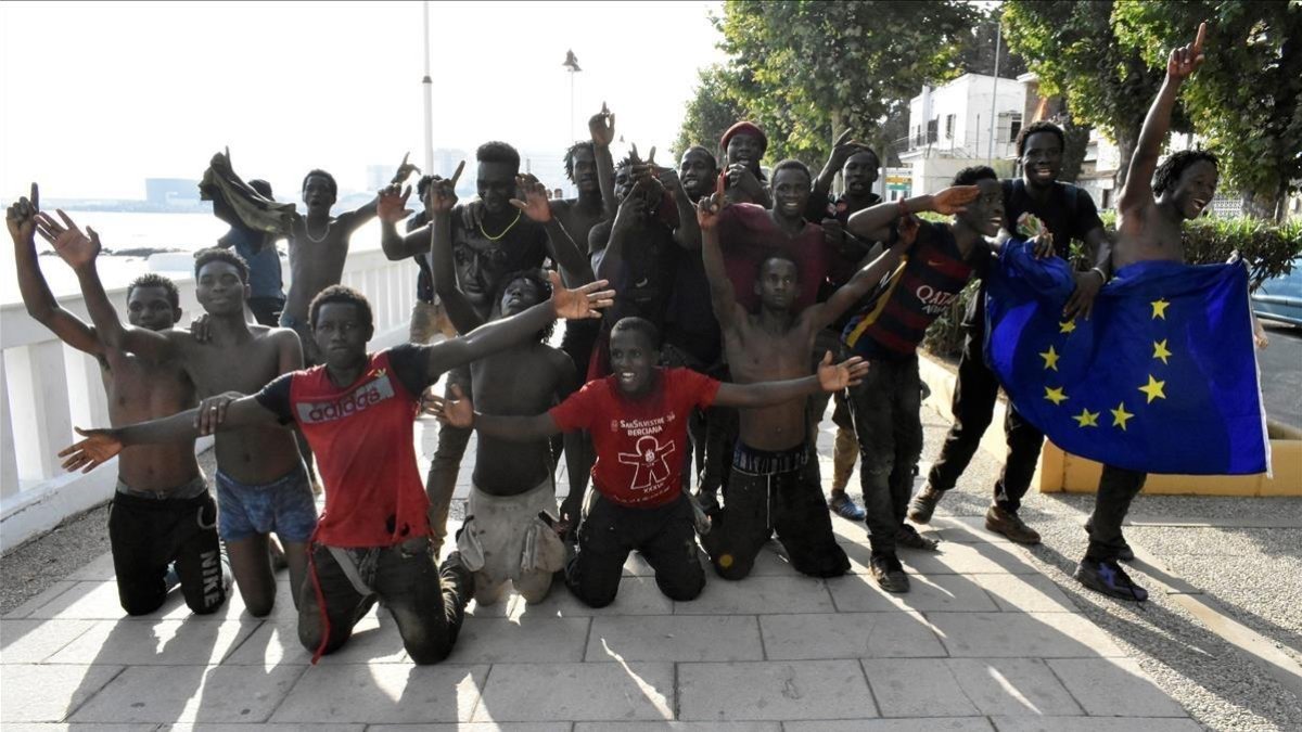 Un grupo de los inmigrantes que ayer saltaron la valla en Ceuta posan con una bandera de la UE.