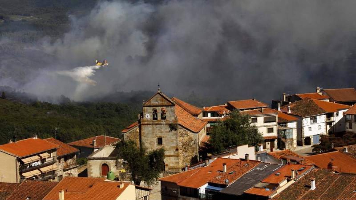 Un helicóptero participa en las labores de extinción del incendio para que no llegue a las casas.