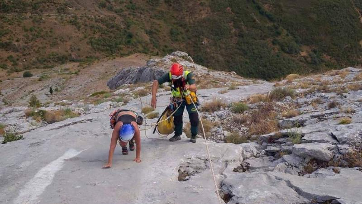 Un agente ayuda a uno de los montañeros a concluir su escalada sano y salvo en Peña Llana. GREIM