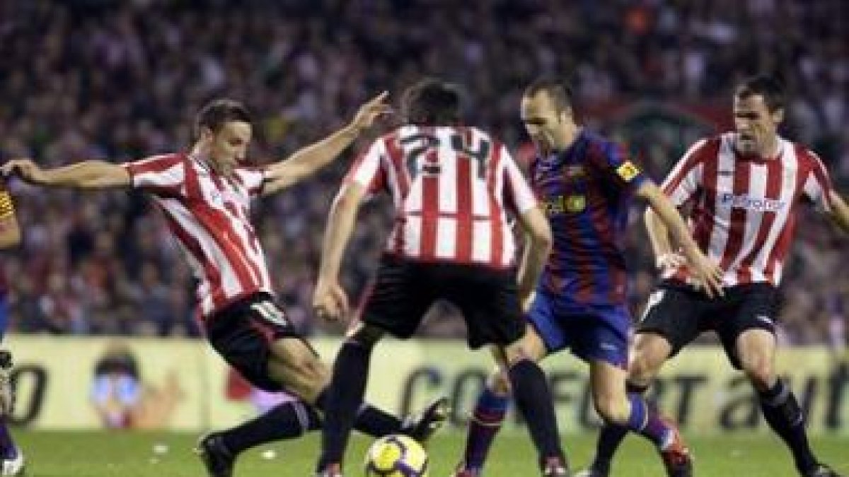 Carlos Gurpegui, Pablo Orbaiz y Javi Martínez frenan al barcelonista Andrés Iniesta.