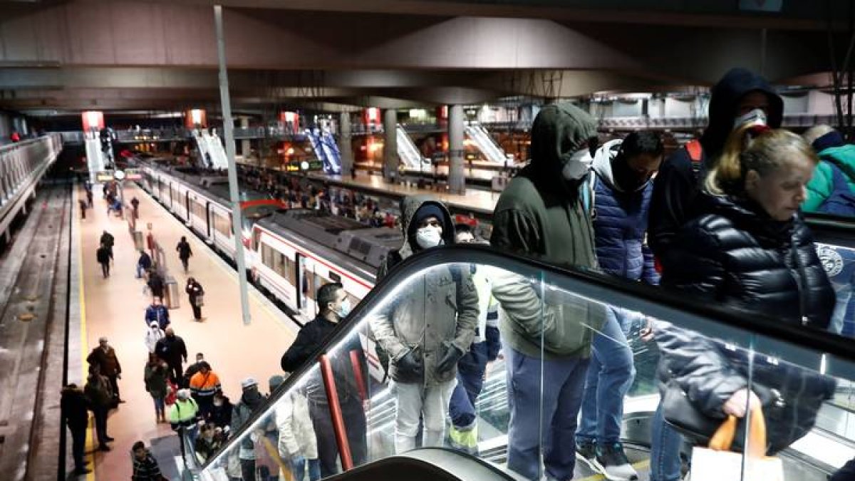 Varios usuarios protegidos con mascarillas transitan a primera hora de este martes la estación de Cercanías de Madrid-Atocha. MARISCAL