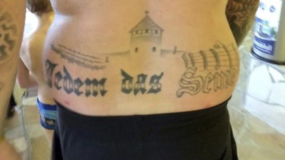 Fotografía facilitada del tatuaje del condenado que reza "Jedem das Seine" ( lit. a cada uno lo suyo) bajo lo que parece el campo de exterminio de Auschwitz.