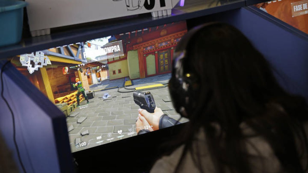Una joven juega con una pistola virtual frente a la pantalla de un videojuego.