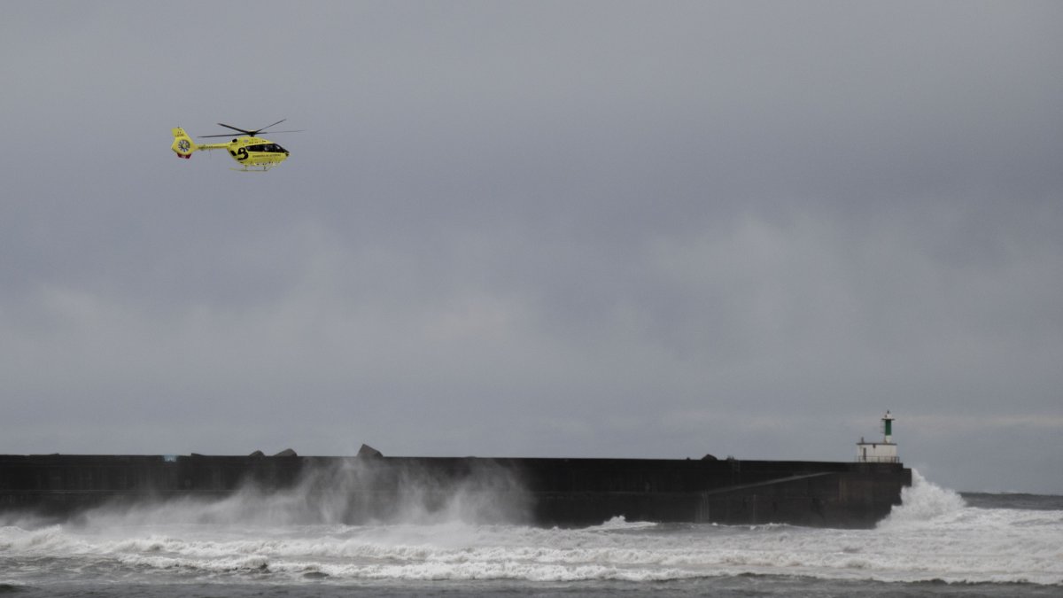 Un helicóptero de rescate trabaja en la localidad asturiana de San Esteban de Pravia este jueves, donde ha fallecido un turista británico que mientras contemplaba el oleaje cayó al agua y fue arrastrado por las olas. Su cuerpo sin vida fue recuperado del mar por un helicóptero de los servicios de emergencias. A menos de siete kilómetros, en el vecino concejo de Cudillero, el fuerte oleaje también dificultó el rescate de una mujer que al parecer fue arrastrada por una ola cuando se encontraba paseando por el puerto pesquero.