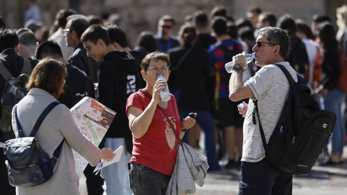 Varios turistas se hidratan este jueves ante la llegada del calor.