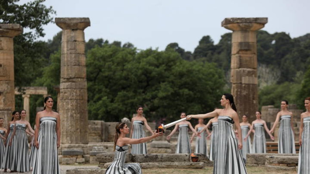 La actriz griega Mary Mina (d), en su papel de Gran Sacerdotisa de Olimpia, encendió la antorcha olímpica durante la tradicional ceremonia que se celebró este martes en las ruinas de la antigua Olimpia.