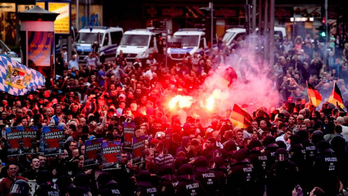 Manifestantes de derecha prenden bengalas mientras enfrentan a la policía antidisturbios durante una manifestación en el lugar donde apuñalaron a un hombre la noche del 25 de agosto de 2018, en Chemnitz (Alemania) hoy, lunes 27 de agosto de 2018. La muerte de un hombre tras una pelea en una fiesta popular en el este de Alemania desató lo que el Gobierno de la canciller Angela Merkel calificó hoy de 