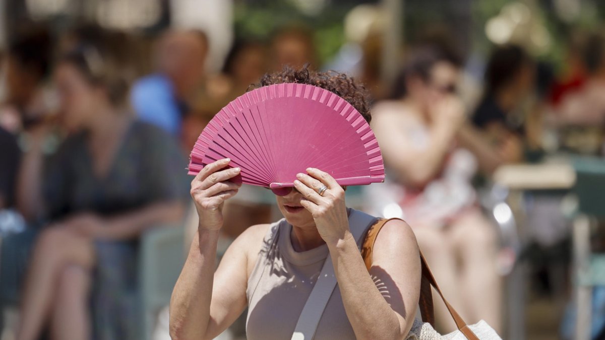 Una mujer se protege con un abanico del sol y del calor en Valencia. EFE/Ana Escobar