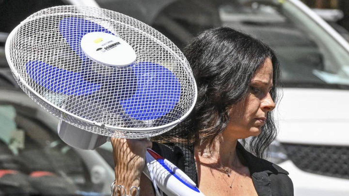 Una mujer lleva un ventilador recién comprado para protegerse del calor.