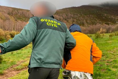 Un agente de la Guardia Civil acompaña a uno de los montañeros rescatados. DL