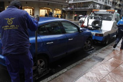 Un policía local acompaña al trabajador de la empresa de la grúa en las intervenciones.