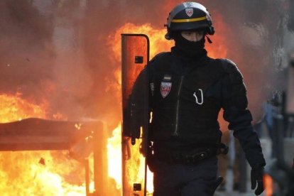 Un policía antidisturbios camina cerca del fuego de una barricada en Toulouse.