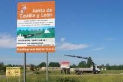 Cartel de las obras en la carretera. Al fondo, el de las viviendas sociales