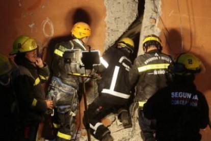 Bomberos chilenos buscan supervivientes entre los escombros.